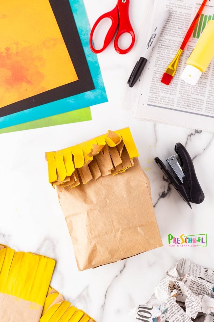 Next, fold the yellow hair strips down neatly and secure the bag closed with a staple.
