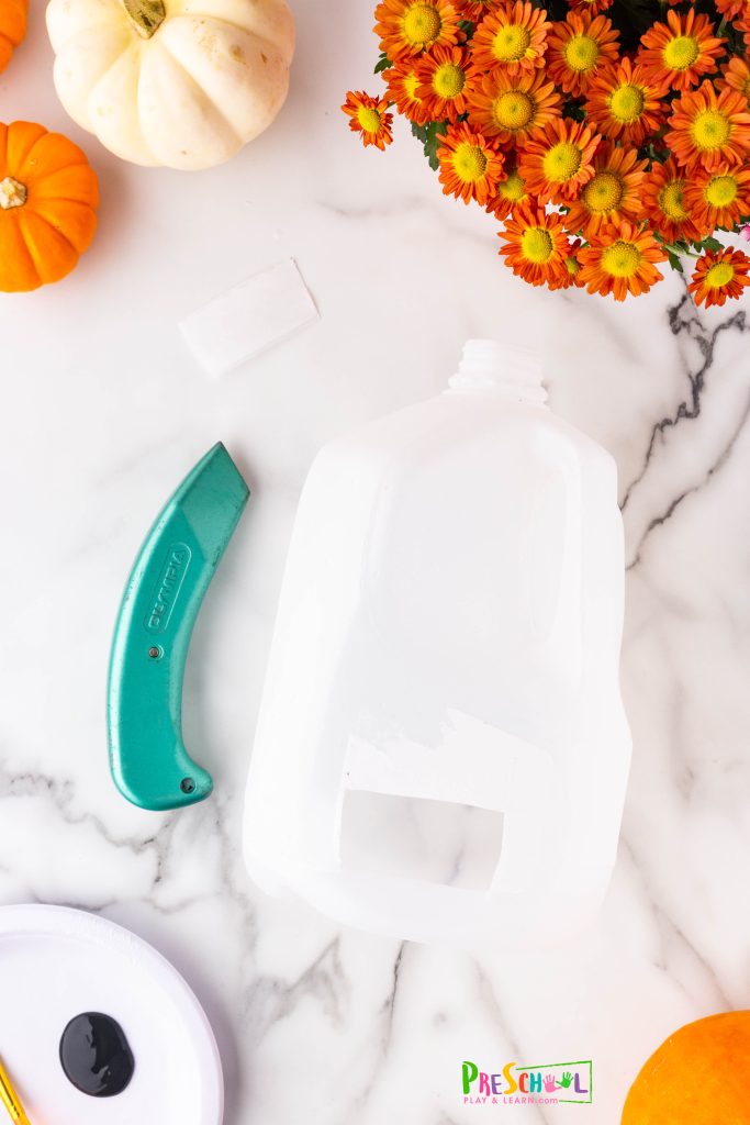 First things first! Begin by rinsing out any leftover milk from your jug. Next, create a small opening at the back of the jug to make room for your tea lights. Remember, it's best for an adult to handle this step using scissors or a box cutter. 