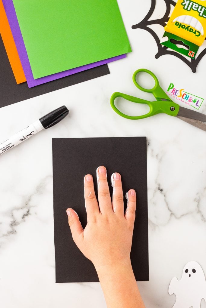 Simply paint their hand with white paint and create handprints on black cardstock paper. Make sure to press down firmly so the print is vibrant and fully visible. 