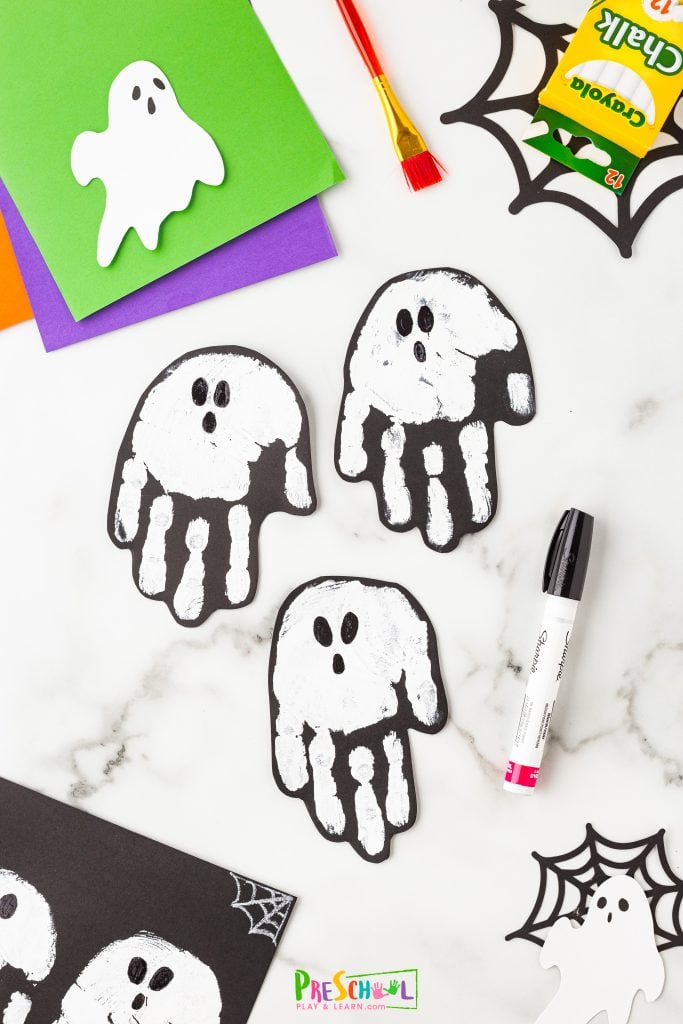 If you're making ghost cards, cut out some handprints to add a spooky touch! Now use black paint or a sharpie to add eyes and a mouth to complete your ghosts.